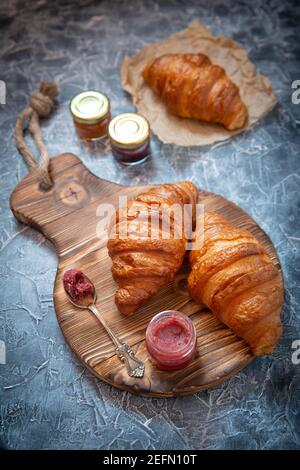 Stile rustico con croissant freschi e marmellata di frutta sul antica tavola di legno Foto Stock