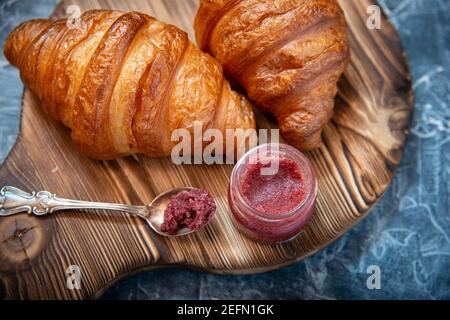 Stile rustico con croissant freschi e marmellata di frutta sul antica tavola di legno Foto Stock