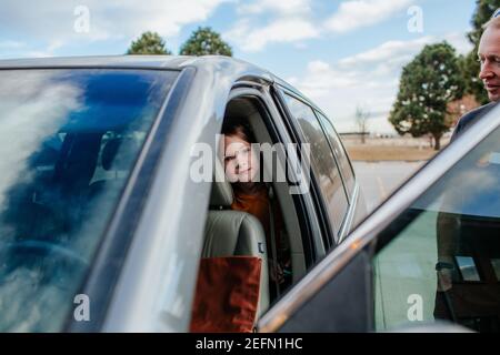 Giovane ragazza che si sbirciava dal sedile posteriore di un'auto prima di un viaggio Foto Stock
