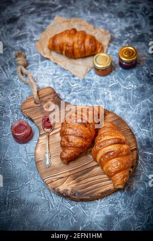 Stile rustico con croissant freschi e marmellata di frutta sul antica tavola di legno Foto Stock