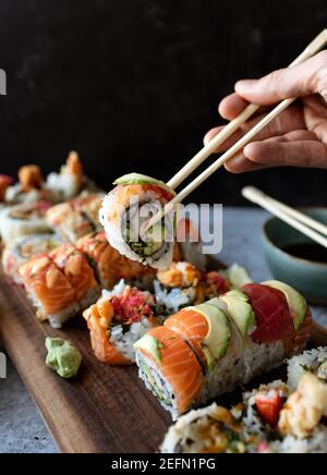 Utilizzare le bacchette per raccogliere un sushi roll off di un piatto. Foto Stock