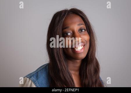 Ritratto di una bella ragazza africana che sorride ed è molto felice. Modello isolato su sfondo grigio. Foto Stock