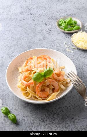 Fettuccine di pasta italiana con gamberi su tavola grigia. Shot verticale. Foto Stock