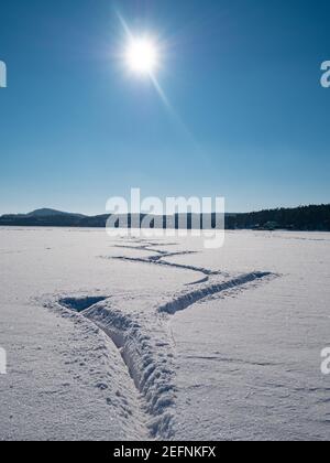 Profonde impronte di pattinatori di ghiaccio in neve fresca. Pattinare su un lago aperto durante una giornata di sole incredibile Foto Stock