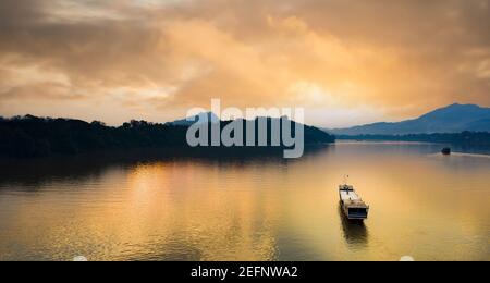 Vista dall'alto, splendida vista aerea di una barca turistica che naviga lungo il fiume Mekong al tramonto. Foto Stock