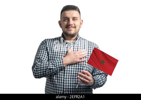 Ragazzo bianco che tiene una bandiera del Marocco e tiene la mano sul suo cuore isolato su uno sfondo bianco con amore per il Marocco. Foto Stock