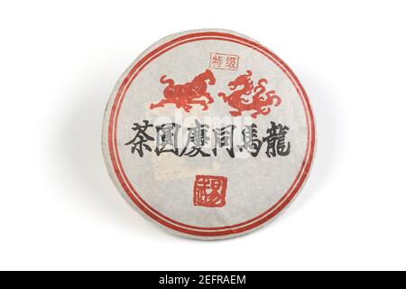 Pu'er o pu-erh, tè cinese fermentato invecchiato o maturato pressato in una forma di torta rotonda. Tè nero cinese avvolto in confezione. Disco isolato su whit Foto Stock
