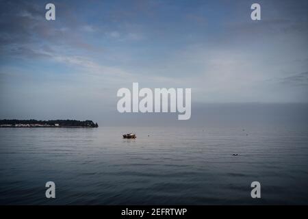 Nuvoloso blu minimalista mare. Barca ormeggiata in mare. Momento di pace Foto Stock