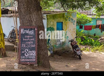 Hunumanahalli, Karnataka, India - 9 novembre 2013: Menu scritto sulla lavagna al di fuori della Sema Guest House. Moto e verde fogliame con dolore alle pareti Foto Stock