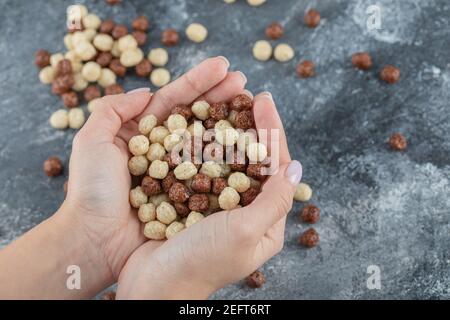 Mani femminili che tengono palle di mais dolci bianche e marroni Foto Stock