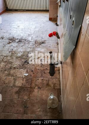 Tubi di acqua fuori del muro in stanza distrutta in vecchio ospedale abbandonato Foto Stock