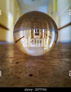 Lungo corridoio del vecchio ospedale abbandonato riflesso in cristallo vetroso lensball Foto Stock