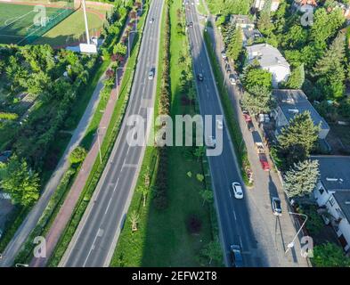 Vista aerea sulle lunghe strade della città con pochi edifici di automobili e lunghe ombre al tramonto Foto Stock