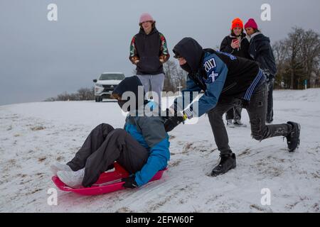 Fiore Mound, Texas, Stati Uniti. 17 Feb 2021. 2/17/21, Flower Mound, Texas - i texani hanno trovato il modo di trasformare questa tempesta invernale in un'esperienza divertente. Un gruppo di adolescenti trascorre la serata in slitta con i loro amici. Credit: Chris Rusanowsky/ZUMA Wire/Alamy Live News Foto Stock