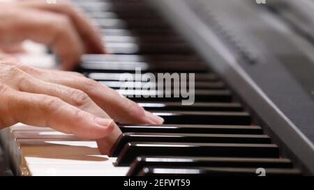 Una vista ravvicinata delle mani maschili che suonano dolcemente un pianoforte tradizionale, premendo i tasti. Riproduzione di musica tema musicale concetto. Foto Stock