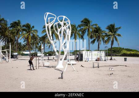 Un uomo si prende una pausa dall'allenarsi alla stazione di allenamento all'aperto di Lummus Park conosciuta come Muscle Beach, a Miami Beach, Florida Foto Stock