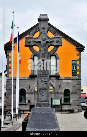 Cashel, County Tipperary, Irlanda. Grande croce celtica nel centro della città l'edificio colorato sullo sfondo è il Cashel Heritage Centre. Foto Stock