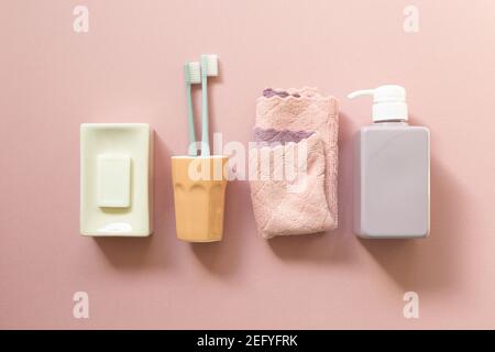 Prodotti da bagno spa. Saponetta, spazzolino da denti, asciugamano, flacone di shampoo su sfondo rosa. Vista dall'alto Foto Stock