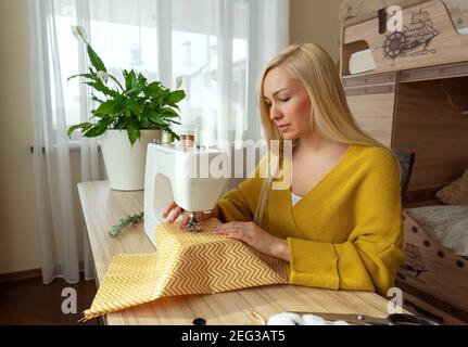 Una donna si siede alla macchina da cucire Foto Stock