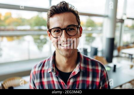 Ritratto di un allegro professionista in carica. uomo d'affari in abiti casual che indossa occhiali che guarda la macchina fotografica e sorride. Foto Stock