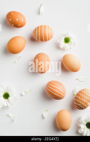 Eleganti uova di Pasqua e fiori di primavera su sfondo bianco. Buon concetto minimo di pasqua. Disposizione piatta, vista dall'alto. Foto Stock