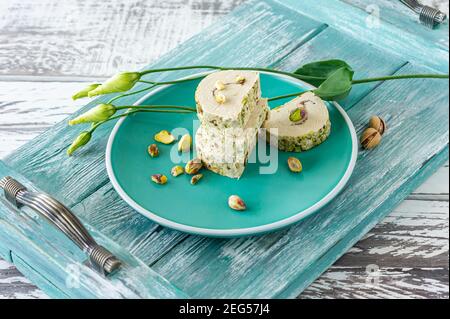 orientare il pistaschio a fette halva. dolce su un piatto con fiori. Foto Stock