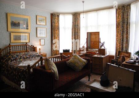 Camera da letto in Cragside Northumberland UK divano vecchia casa grande foto muro arte letto vittoriano cuscini oro cornice ringhiera tende in legno Foto Stock