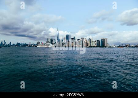 Skyline di New York City con una nave da crociera di giorno, vista da Ellis Island Foto Stock