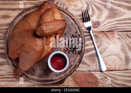 Mezzo pollo affumicato su tavola di legno con salsa e pepe. Pollo arrosto fritto su tavolo di legno con spazio copia Foto Stock