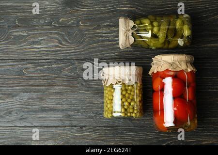Vasetti con pomodori, cetrioli e piselli sottaceto su sfondo ligneo Foto Stock