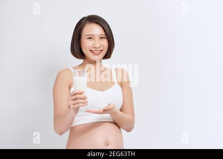 Donna incinta che beve latte bianco Foto Stock