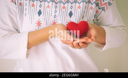 Le donne indossano una camicia bianca che tiene a mano il cuore rosso. Concetto di amore, speranza, felice Valentino, sanità,donazione di organi,assicurazione, medico, Giornata mondiale del cuore, Foto Stock