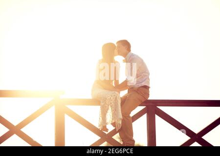 gli sposi novelli baciano sul cancello al sole Foto Stock