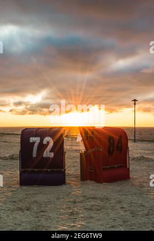 Sedie da spiaggia in vimini sulla spiaggia di Neuharlingersiel al tramonto, Frisia orientale, bassa Sassonia, Germania Foto Stock