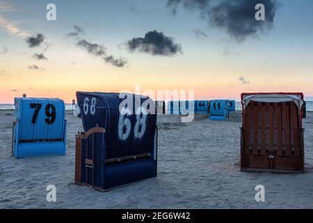 Sedie da spiaggia in vimini sulla spiaggia di Neuharlingersiel al crepuscolo, Frisia orientale, bassa Sassonia, Germania Foto Stock