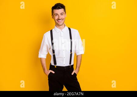 Ritratto fotografico di allegro Signore sorridente positivo che indossa magliette sospenders isolato su uno sfondo di colore giallo vivace Foto Stock