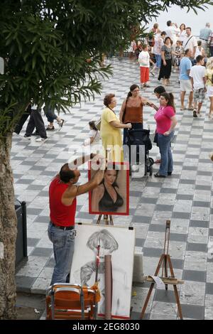 Artista di strada e pittore in un mercato di strada in un vicolo nel centro storico di Taormina in provincia di Sicilia in Italia. Italia, Sicilia, Foto Stock