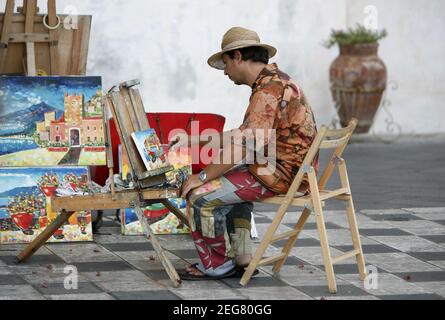 Artista di strada e pittore in un mercato di strada in un vicolo nel centro storico di Taormina in provincia di Sicilia in Italia. Italia, Sicilia, Foto Stock