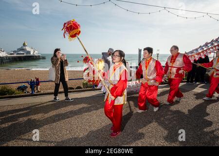 Gli artisti sfilano lungo il lungomare di fronte all'Eastbourne Pier durante le celebrazioni del Capodanno cinese a Eastbourne, Sussex, Regno Unito. Foto Stock