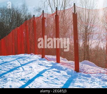 Rete di sicurezza rossa al bordo di una pista di sci alpino. Foto Stock