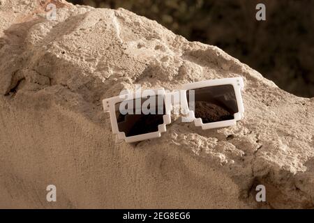 Occhiali da sole in pixel bianchi con lenti nere da indossare in una giornata di sole. Messa a fuoco selettiva Foto Stock