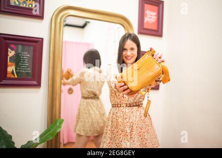 Giovane ragazza che li sceglie e li prova sopra in un deposito Foto Stock