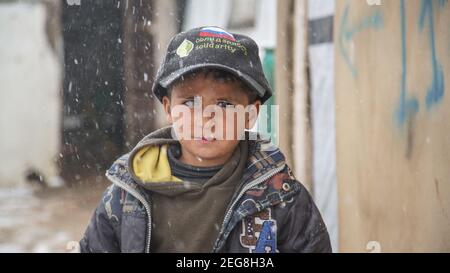 Siriano Refugee Little Boy nel campo di rifugio di Aarsal a. I confini libanesi siriani in inverno neve tempesta Blizzard Foto Stock