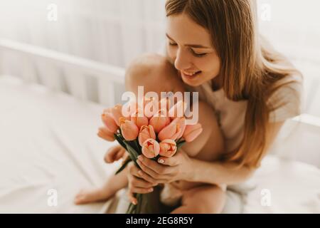 Buon giorno della Madre, mamma felice con il bambino, congratulazioni mamma per la vacanza e dare fiori Foto Stock