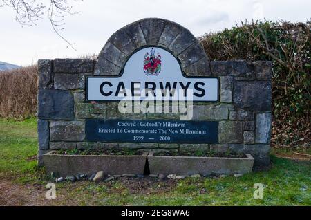 Caerwys, Flintshire; Regno Unito: 11 febbraio 2021: Un cartello con il nome costruito in pietra all'ingresso di Caerwys incorpora lo stemma ufficiale della città. Il segno è stato Foto Stock