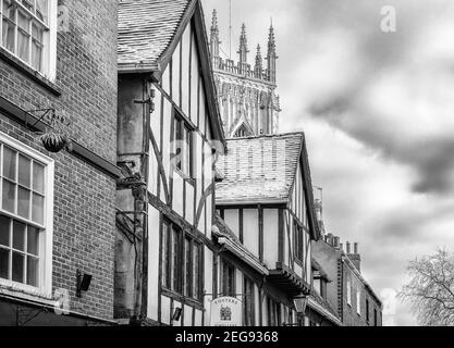 Un vecchio edificio a graticcio con neve sul tetto. Una delle torri non York Minster è sullo sfondo e un cielo pieno di nuvole è sopra. Foto Stock