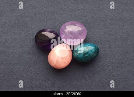 Gemme multicolore, pietre rotolanti tagliate. Ametista, quarzo rosa, apatite su sfondo grigio. Foto Stock