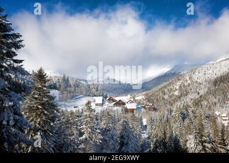 chalet innevati in una valle sovrastata da montagne, paesaggio invernale, alpi europee Foto Stock