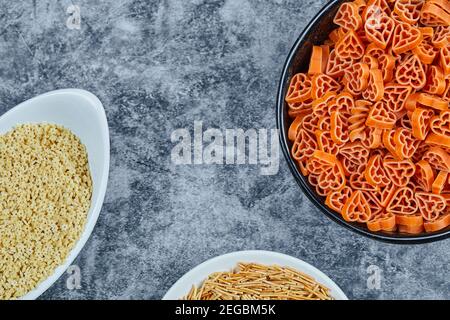 Vari tipi di pasta secca sullo sfondo marmoreo Foto Stock