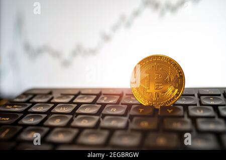 Moneta Bitcoin dorata sulla tastiera con grafico di sollevamento. Concetto di criptovaluta, estrazione, stock Foto Stock